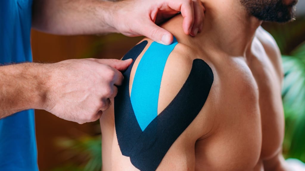 A man with a black and blue tape on his shoulder.